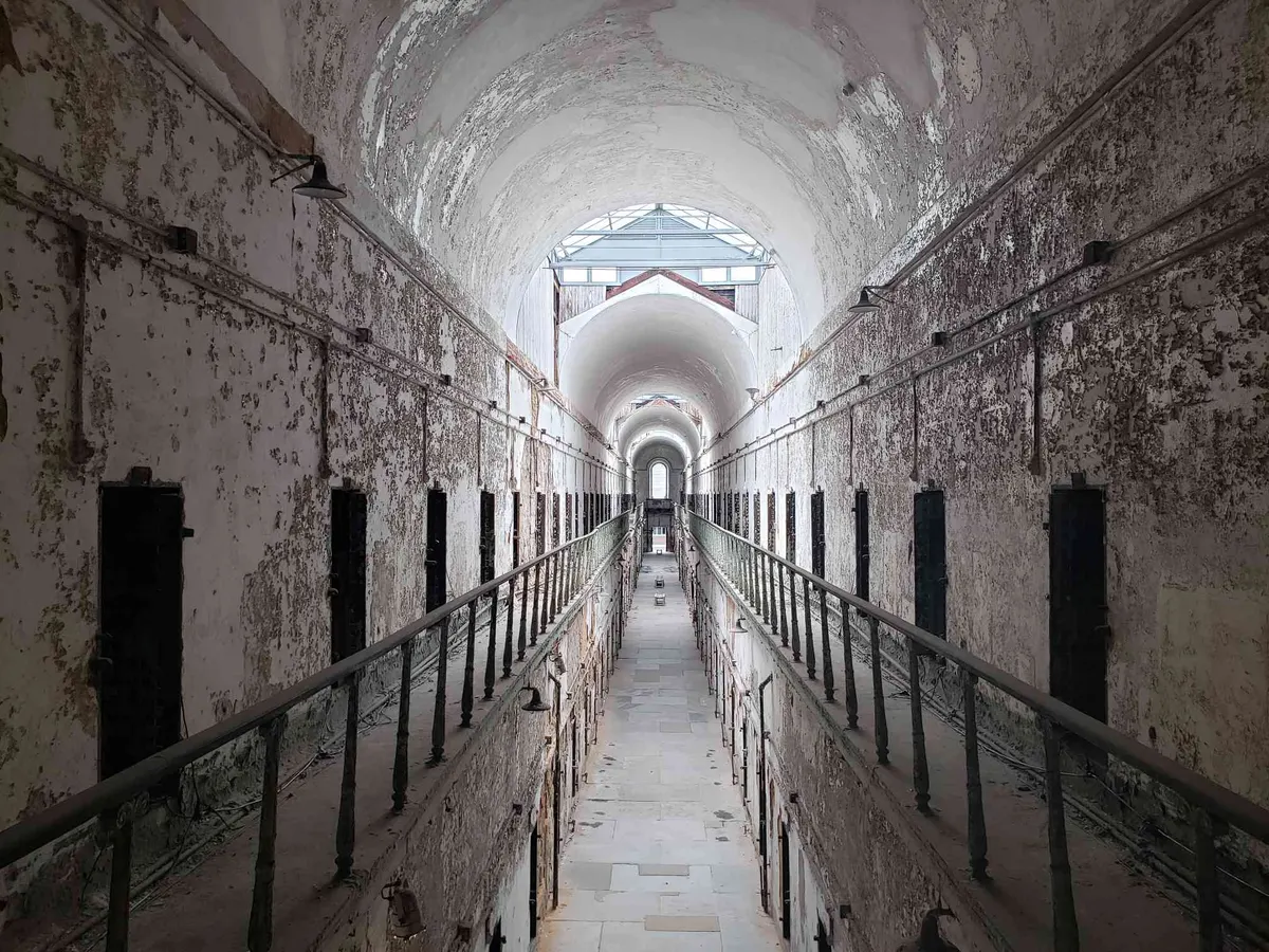 A long vaulted cellblock corridor with two levels of cell doors at Eastern State Penitentiary